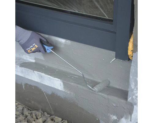 Application d''un scellant avec un rouleau sur un mur de maison.