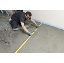 Artisan nivelant la chape avec une règle.