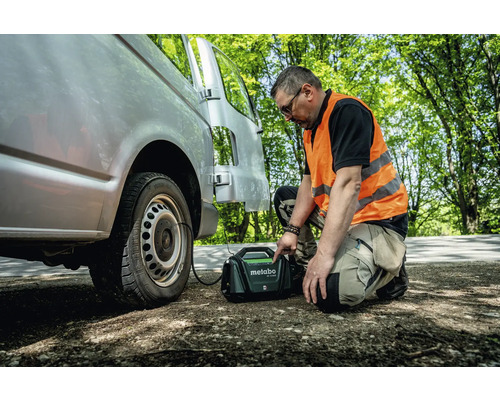 Ein Mann befüllt einen Reifen eines Transporters mit einem mobilen Kompressor von Metabo.