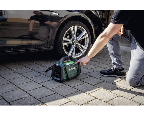 Metabo Akku-Kompressor neben einem Auto auf Pflastersteinen