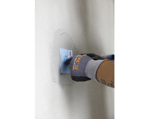 Person verspachtelt eine Wand mit einem Spachtel