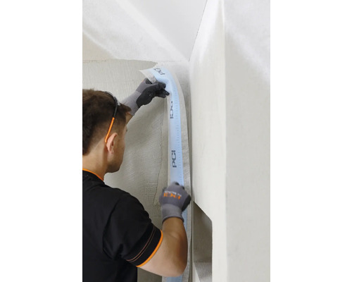 Handwerker befestigt Dichtband von PCI in einer Ecke