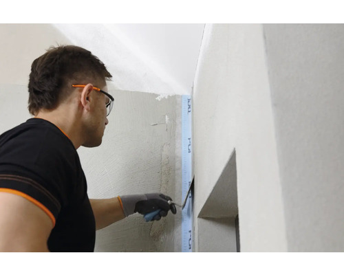 Eine Person glättet Putz an einer Wand mit einer Spachtel.