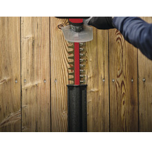 Heckenschere im Einsatz vor Holzzaun