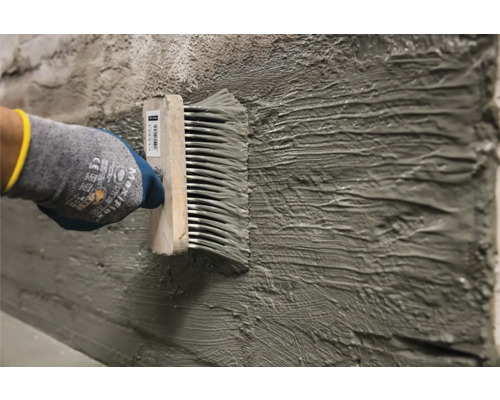 Auftragen von Kleber mit einem Klebekamm auf einer Wand