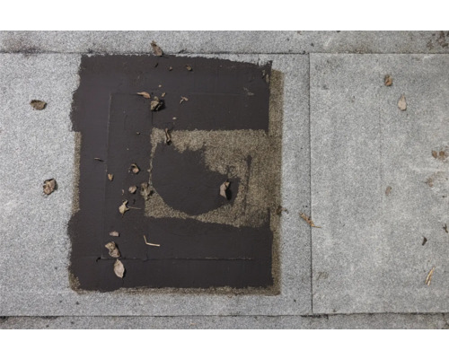 Vue détaillée d''une surface pavée réparée avec des patchs de bitume sur des pavés.