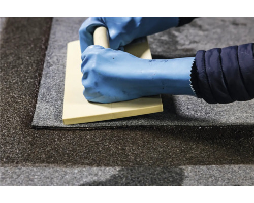 Handwerker mit Glättkelle beim Verlegen von Fliesen