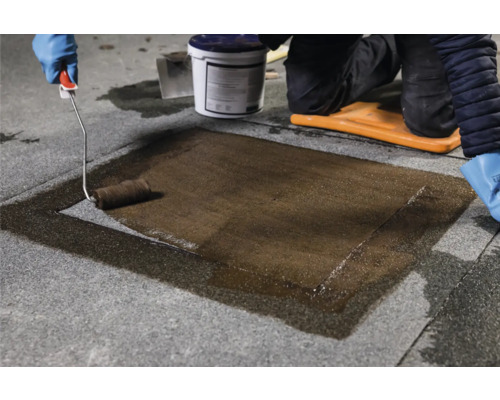 Person trägt Abdichtung mit einer Farbwalze auf Stein auf.