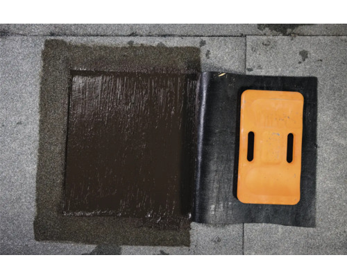 Detailansicht einer abgedichteten Dachreparaturstelle mit Bitumen und Abdichtungsbahn