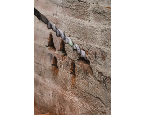 Bohrer bohrt ein Loch in eine Ziegelwand.