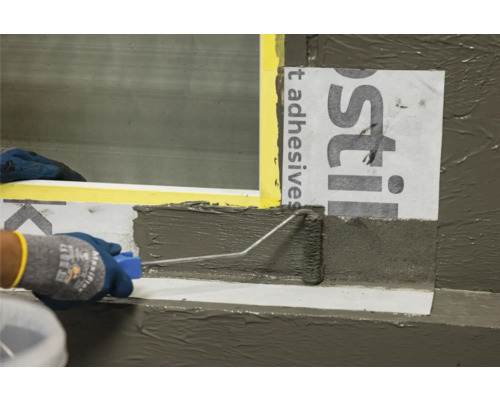 Application de mastic avec un rouleau à peinture sur un rebord de fenêtre