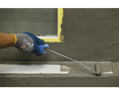 Eine Person trägt eine Beschichtung mit einer Walze auf