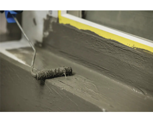 Auftragen von Dichtungsschlämme mit Farbroller auf einer Fensterbank.