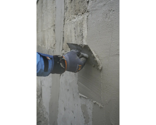 Auftragen von Putz auf eine Wand mit einer Glättkelle