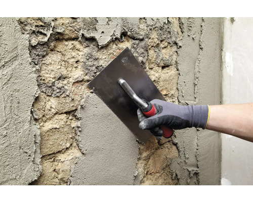 Maurer verputzt mit einer Glättkelle eine Wand.