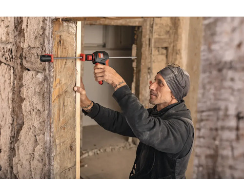 Ein Mann verwendet ein Spreizwerkzeug zur Installation eines Türrahmens.