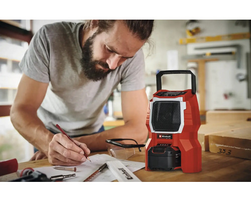 Un homme planifie un projet à côté d''une radio de chantier Einhell rouge