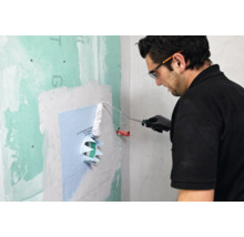 Un homme applique du mortier d''étanchéité sur un manchon d''étanchéité avec un rouleau à peinture.