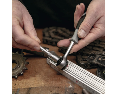 Une personne utilise un cliquet avec un embout de douille sur un établi.