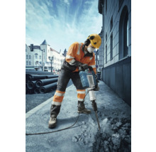 Un ouvrier du bâtiment utilise un marteau-piqueur pour travailler le béton sur un chantier