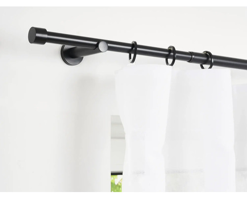 Gardinenstange aus Metall mit Gardinenringen an einer weißen Wand