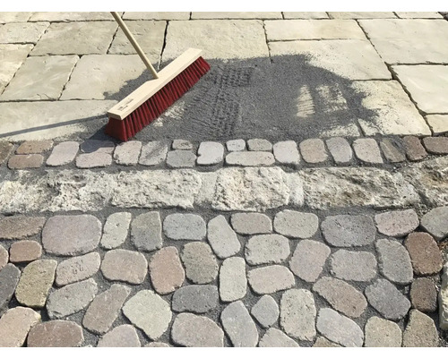 Scène de nettoyage de joints de pavés avec un balai