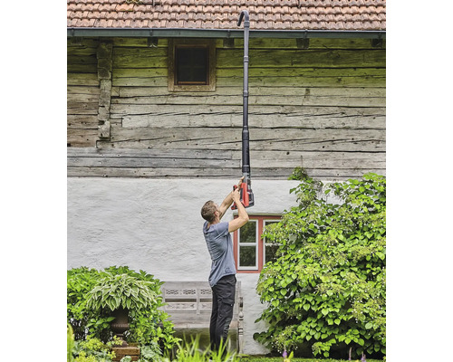 Mann reinigt Dachrinne mit Dachrinnenreiniger vor einem Haus