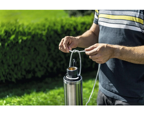 Mann befestigt ein Seil an einer Tauchdruckpumpe