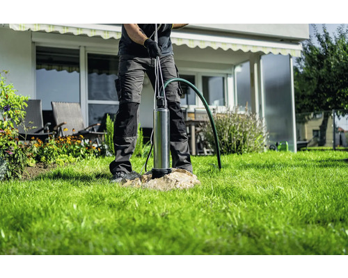 Ein Mann installiert eine Tiefbrunnenpumpe im Garten.