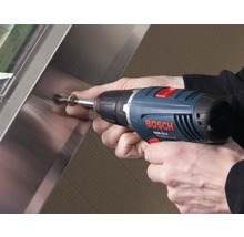 Ein Mann schraubt mit einem Akkuschrauber eine Schraube in eine Metallplatte.