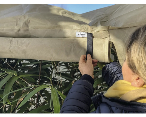 Une personne fixe une housse de protection à l''extérieur avec une fermeture velcro