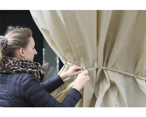 Eine Frau befestigt eine Abdeckung, wahrscheinlich eine Terrassenabdeckung oder einen Pavillonbezug.
