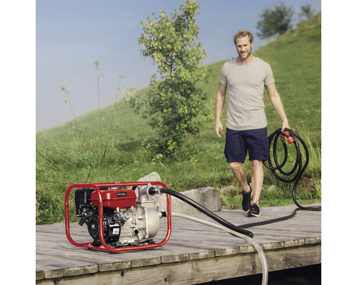 Benzin-Wasserpumpe auf Holzsteg mit Mann, der einen Schlauch hält