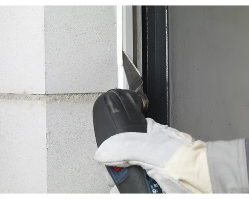 Person verwendet ein Multifunktionswerkzeug zum Schneiden an einer Wand