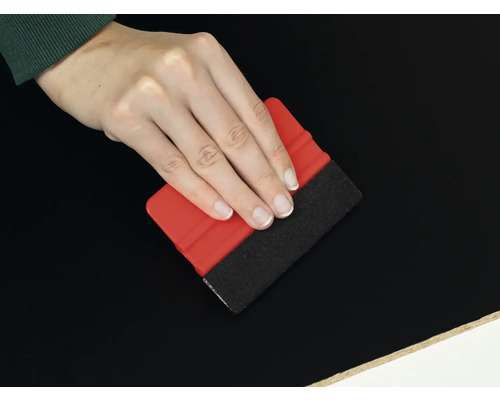 Main avec raclette pour appliquer du film sur une surface