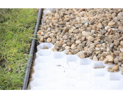 Nahaufnahme eines mit Kies gefüllten Rasengittersteins neben einem Rasen