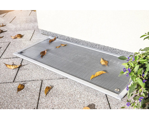 Kellerfensterabdeckung mit Laubschutzgitter auf Pflastersteinen