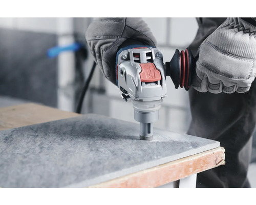 Bohren einer Fliese mit einem Winkelschleifer mit Diamantbohrkrone