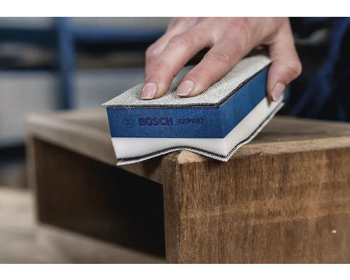 Eine Person schleift ein Holzmöbelstück mit einem Schleifschwamm von Bosch Expert