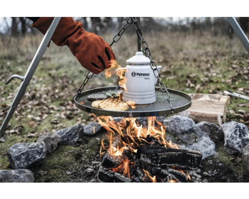 Grille avec aliments, bouilloire et gant au-dessus d''un feu ouvert