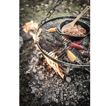 Gril suspendu au-dessus d''un feu ouvert avec steak, légumes et haricots dans une poêle.