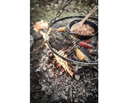 Gril suspendu au-dessus d''un feu ouvert avec steak, légumes et haricots dans une poêle.