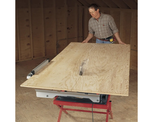 Un homme coupe une planche de bois avec une scie circulaire sur table.