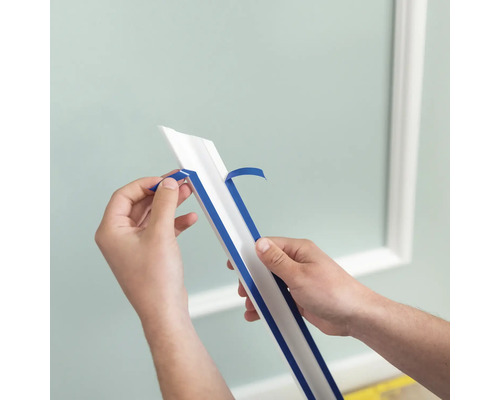 Eine Person entfernt die Schutzfolie von einer Zierleiste zur Wandgestaltung.