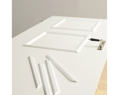 Des moulures décoratives et une poignée de porte sont posées sur une porte.