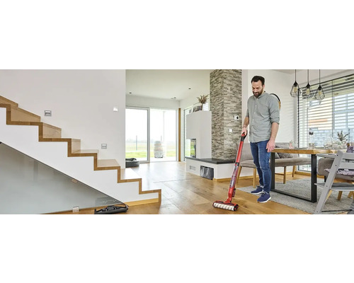 Mann reinigt Holzboden mit Akku-Wischsauger in modernem Wohnraum