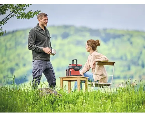 Ein Paar entspannt im Freien mit einer Powerstation auf einem Holztisch.