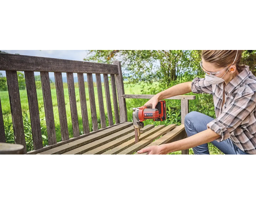 Eine Frau schleift eine Holzbank mit einem Bandschleifer von Einhell.