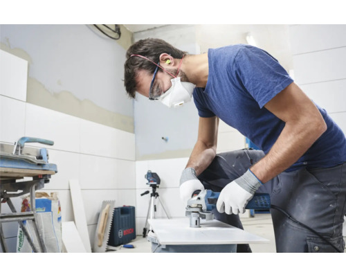 Handwerker bearbeitet Fliese mit Winkelschleifer im Innenraum.