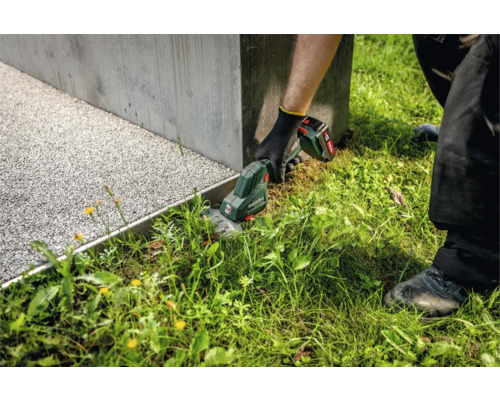 Akku-Rasenkantenschere im Einsatz zum Schneiden von Gras an einem Beetrand